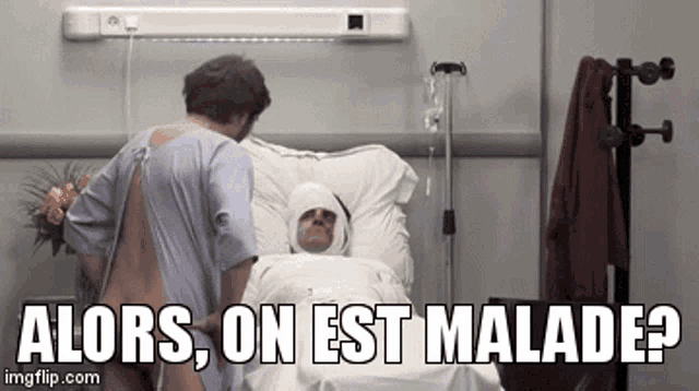 a man in a hospital gown is standing next to a man in a hospital bed with a bandage on his head ..