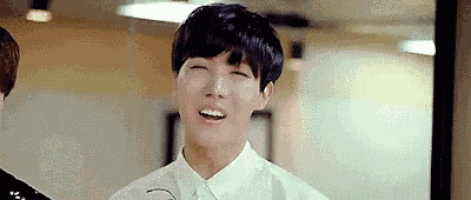 a young man is smiling with his eyes closed while wearing a white shirt .