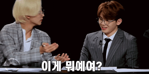 a man in a suit and tie is talking to another man in a plaid jacket