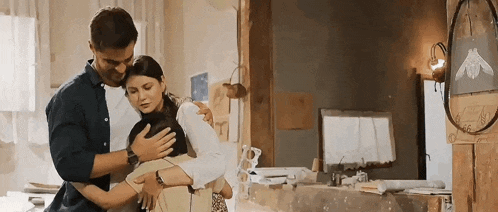 a man and a woman are hugging each other in a kitchen .