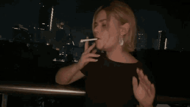 a woman in a black shirt is smoking a cigarette