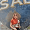 a woman in sunglasses is standing in front of a universal studios sign .
