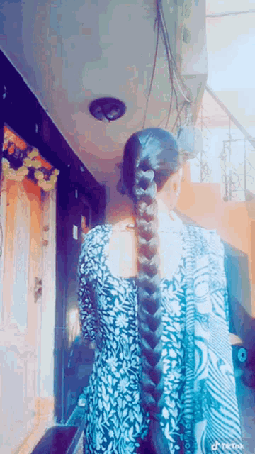 a woman with a braided ponytail is standing in front of a building with tiktok written on the bottom