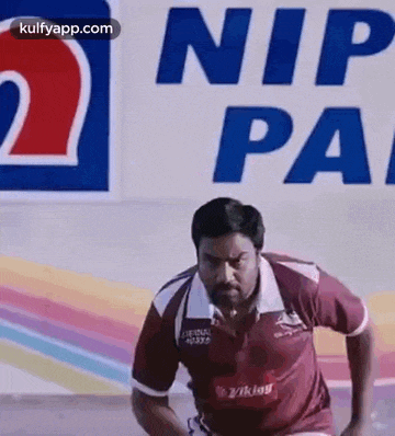 a man is running on a track in front of a sign that says nip pa .