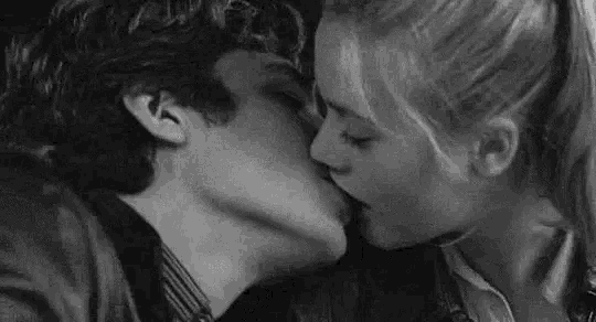 a man and a woman are kissing in a car in a black and white photo .