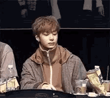 a young man is sitting at a table with a bag of chips and a bottle of water .