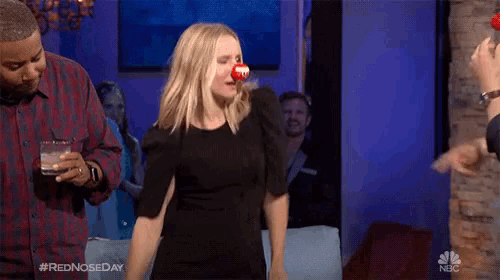 a woman wearing a red nose has the hashtag #rednoseday on her shirt