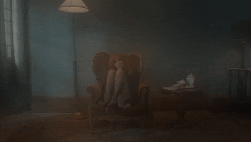 a woman sits in a chair in a dark room