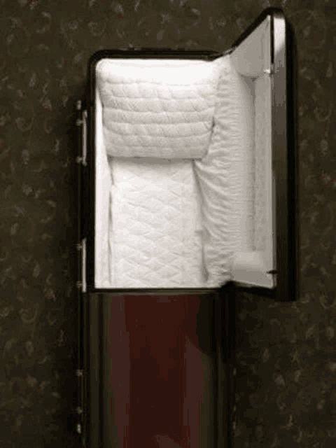 a black coffin with the lid open and a white blanket on the inside