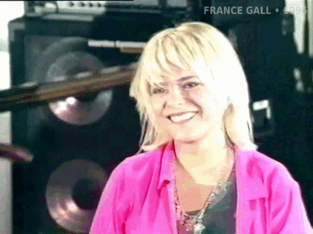 a woman in a pink shirt is smiling in front of a speaker that says france gall on the bottom