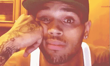 a man wearing a hat and a tank top is making a funny face .