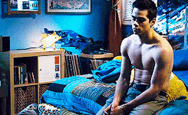 a shirtless man is sitting on a bed .