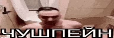 a shirtless man is standing in a bathroom next to a toilet with a foreign language written on it .