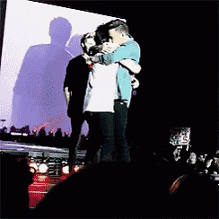 two people hugging on a stage with a sign that says ' s ' on it