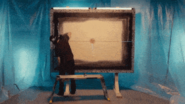 a man is standing on a ladder in front of a large canvas