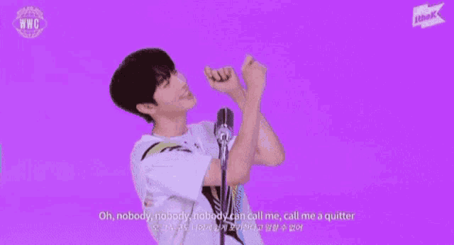 a young man is standing in front of a microphone with his hands in the air and singing into it .