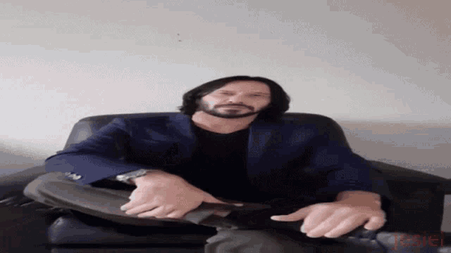 a man with a beard is sitting in a chair with his feet crossed