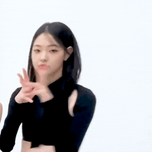 a woman in a black crop top is making a peace sign .