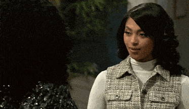 two women are talking to each other and one is wearing a white turtleneck