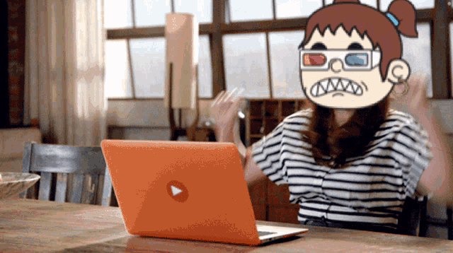 a woman wearing 3d glasses is sitting at a table with an orange laptop