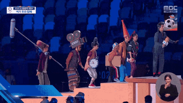 a group of people standing on a stage with a camera on their head and a sign that says ' mbc ' on it