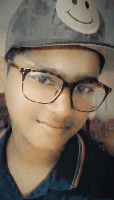a boy with glasses and a hat with a smiley face on it