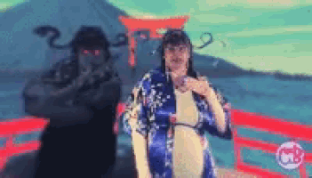 a woman in a blue kimono is standing next to a man in a black hat .