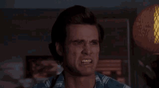 a man in a plaid shirt is making a funny face while standing in front of a lamp .