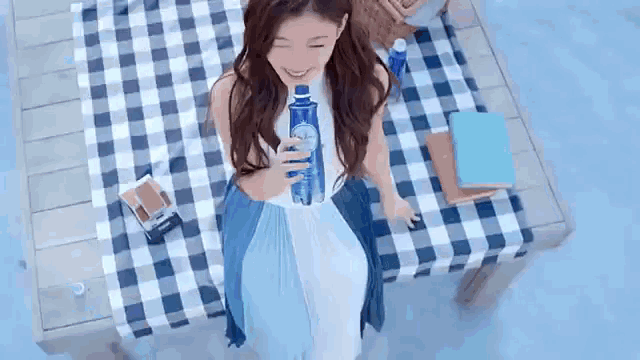 a woman is sitting on a picnic table drinking from a bottle of water .