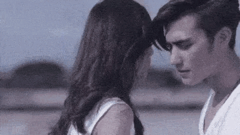 a man and a woman are touching their foreheads and looking at each other .