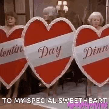 a group of women are standing next to each other holding valentine 's day signs in the shape of hearts .