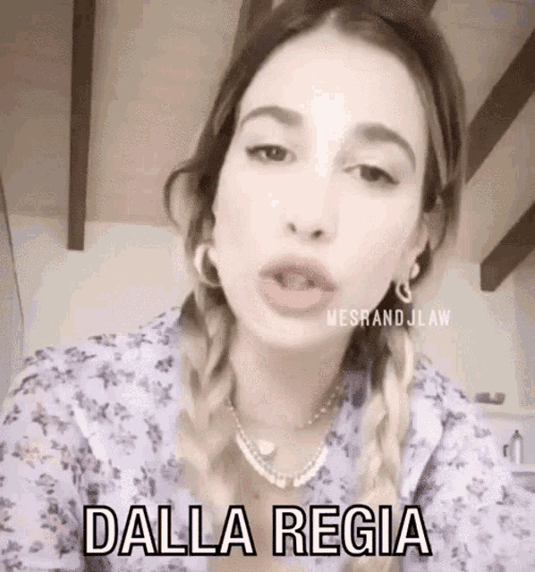a woman is wearing a purple shirt and earrings and says dalla regia .