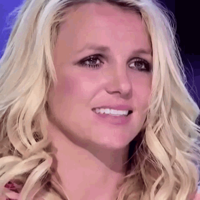 a close up of a woman 's face with blonde hair and a smile on her face