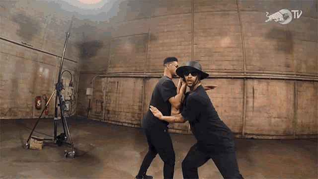 two men are dancing in a dark room with a red bull tv logo in the background