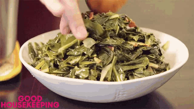 a bowl of collard greens is being stirred with a wooden spoon and says good housekeeping on the bottom