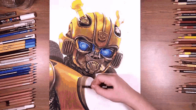 a person is drawing a transformer on a piece of paper surrounded by colored pencils
