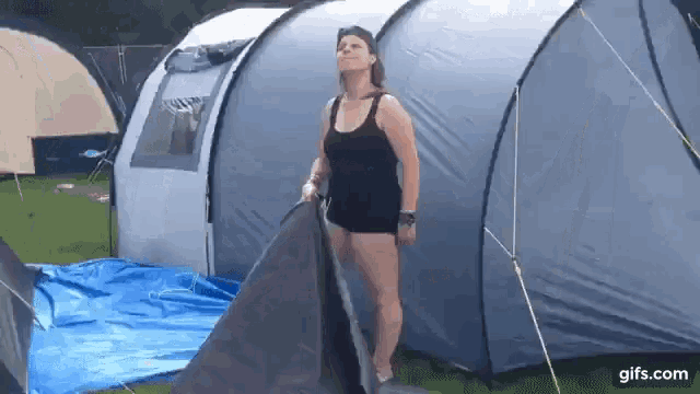 a woman is standing in front of a tent .