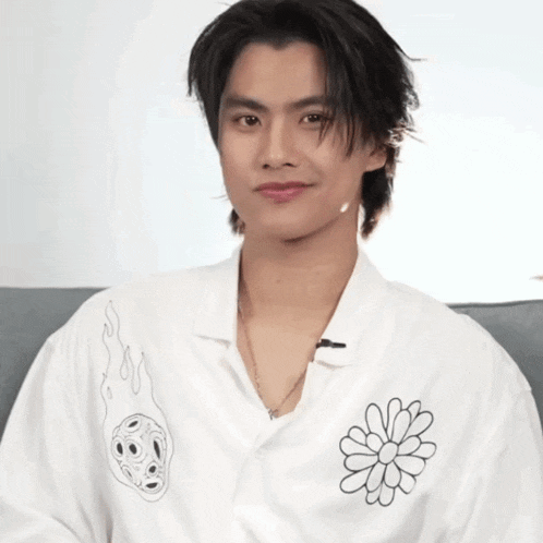 a young man wearing a white shirt with a black flower on it