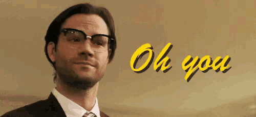a man wearing glasses and a suit is smiling and says oh you .