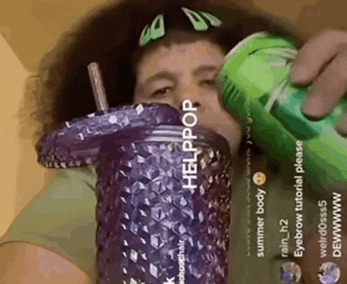 a woman is drinking from a purple cup with a green straw .