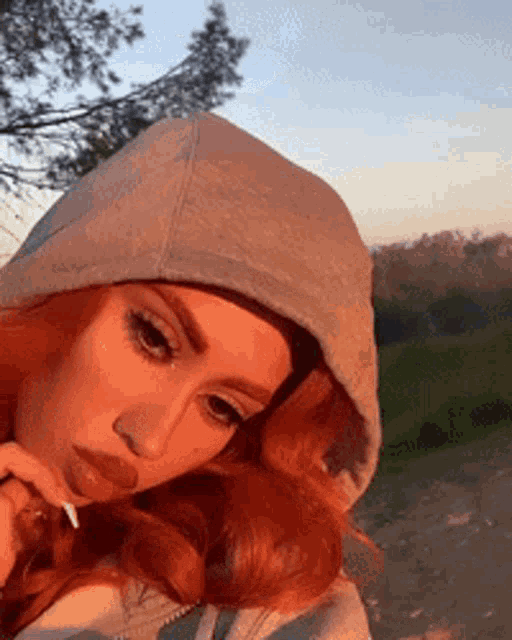 a woman with red hair is wearing a hooded sweatshirt .