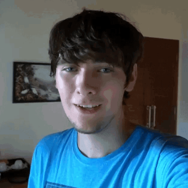 a man in a blue shirt is smiling in front of a picture