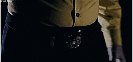 a black jacket with gold stripes on the sleeves is laying on a black surface