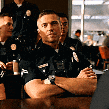 a police officer named bradford sits at a desk with his arms crossed