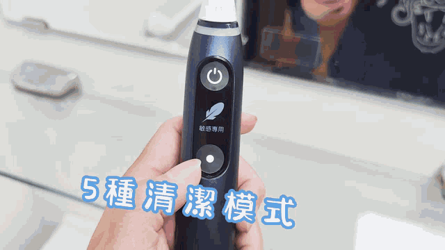 a person is holding a toothbrush in front of a mirror with chinese writing on it