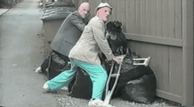 a man with crutches is pushing another man with crutches on a pile of garbage bags