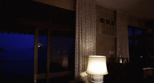 a lamp is lit up in front of a window with a blue sky behind it