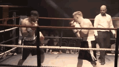 two men are fighting in a boxing ring with a referee watching