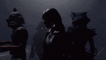 a group of people standing in a dark room with one wearing a mask