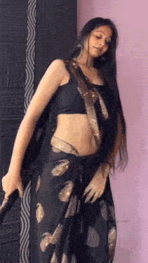 a woman wearing a black crop top and a black saree is dancing .